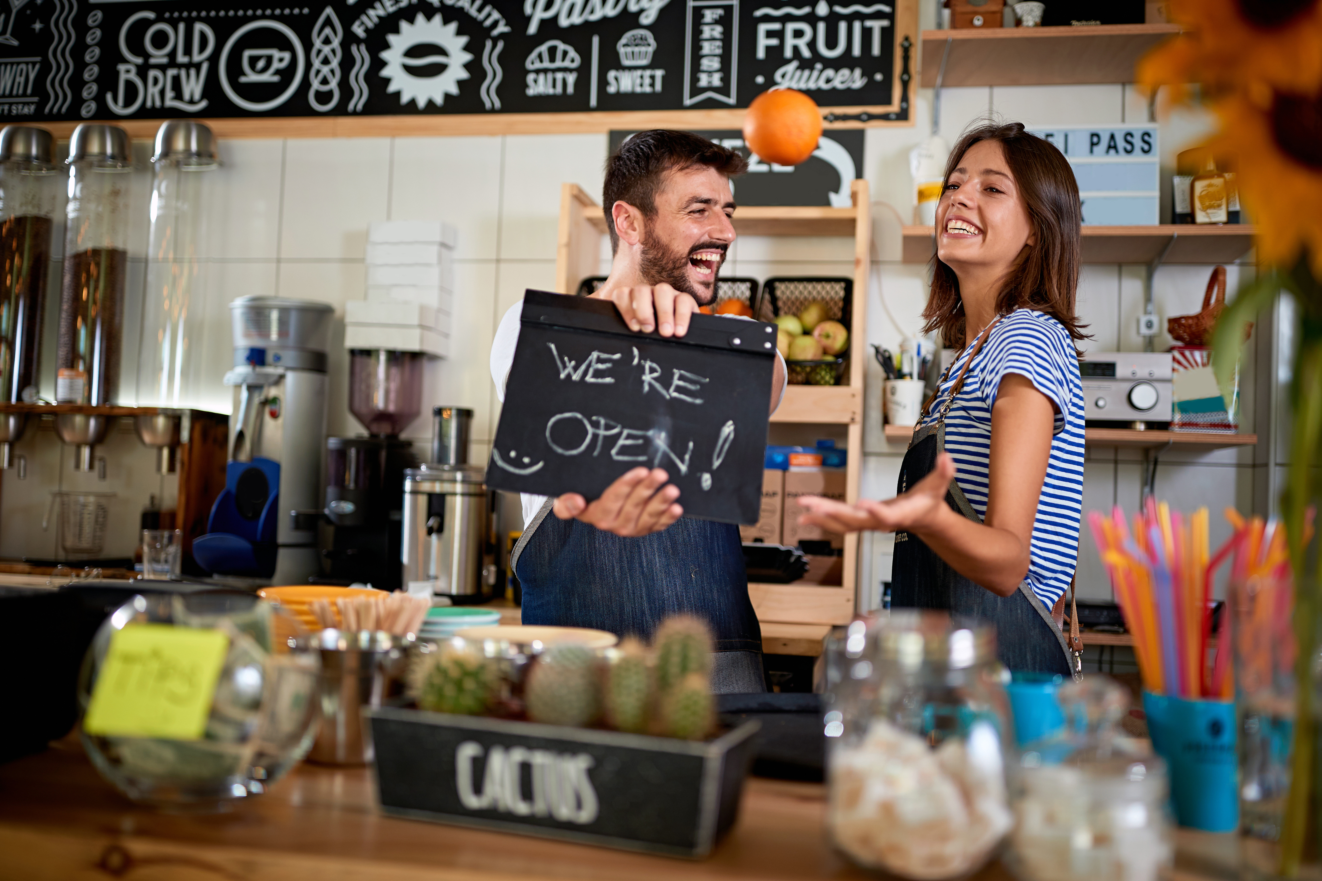 Business owner holding Open Sign. Man and woman opening their store