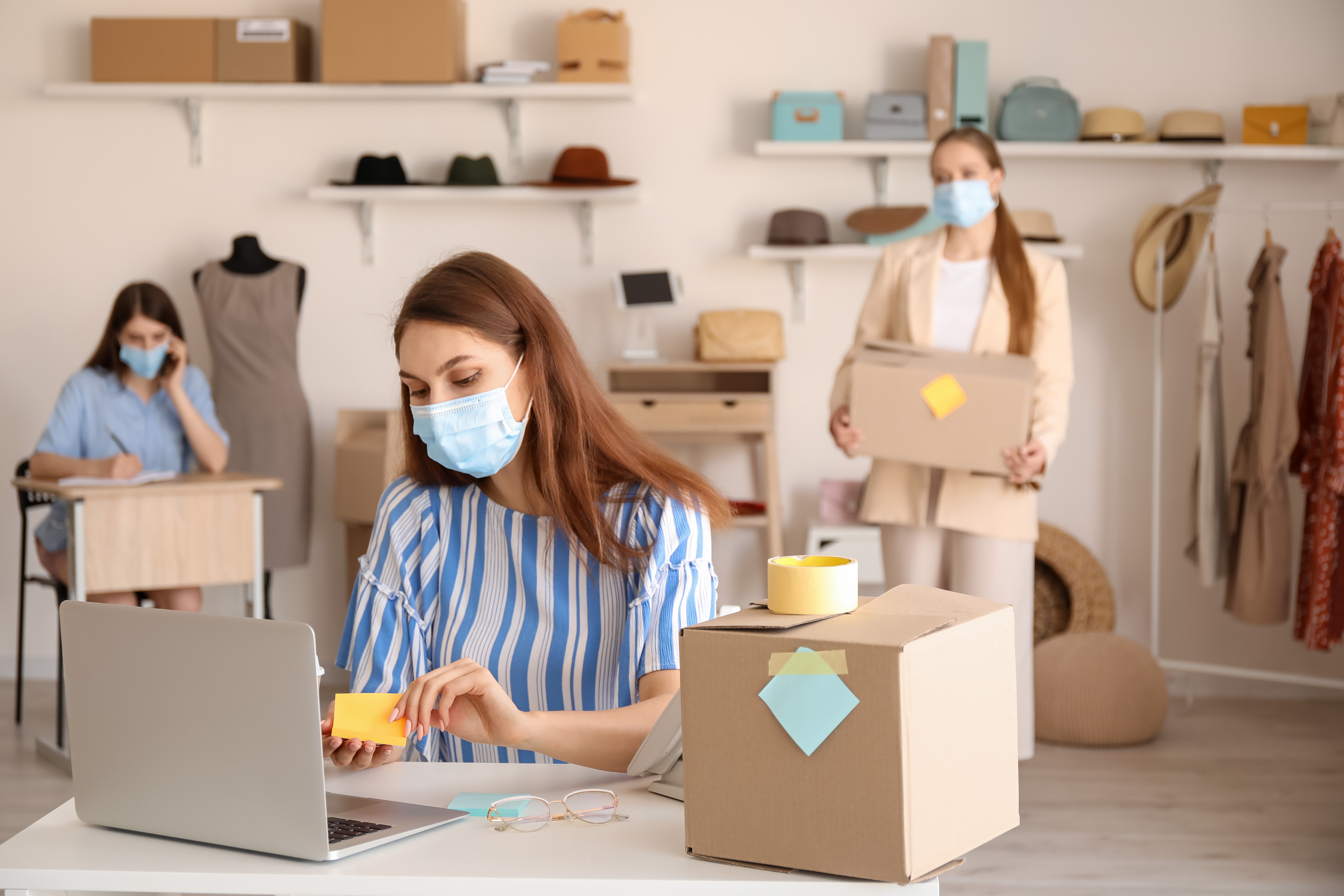 Female business owner in medical mask processing order in shop